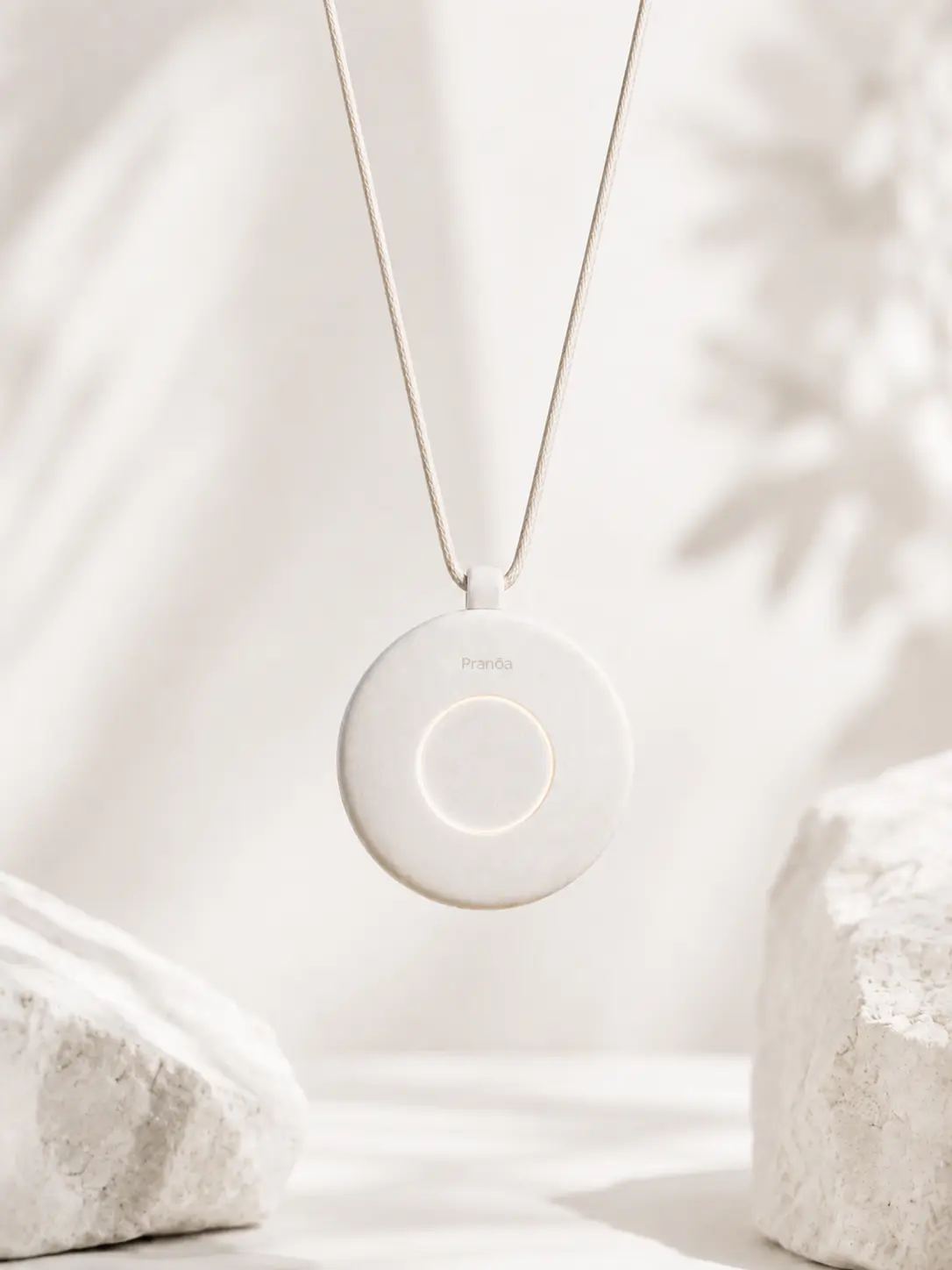 The Pranōa pendant in white, hanging from its woven cord